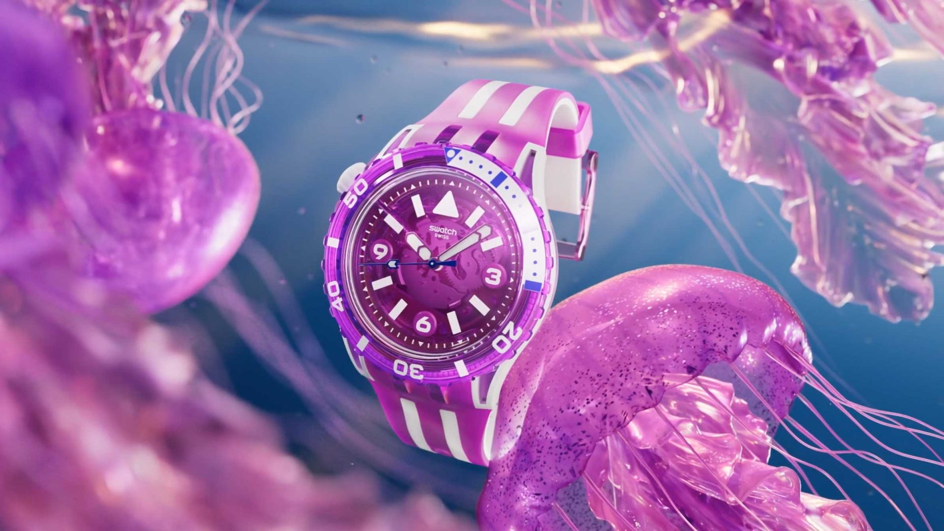 A purple and white striped Swatch wristwatch floats underwater among vibrant pink and purple jellyfish, with a blue background creating an ethereal, dreamy ocean scene inspired by Dada Projects. Frame from Stash Magazine article.