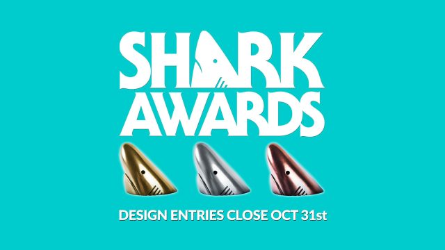 Shark Awards logo above gold, silver, and bronze shark fin trophies, with the text DESIGN ENTRIES CLOSE OCT 31st at the bottom against a teal background for the Sharks-Design-Awards-2026. Frame from Stash Magazine article.