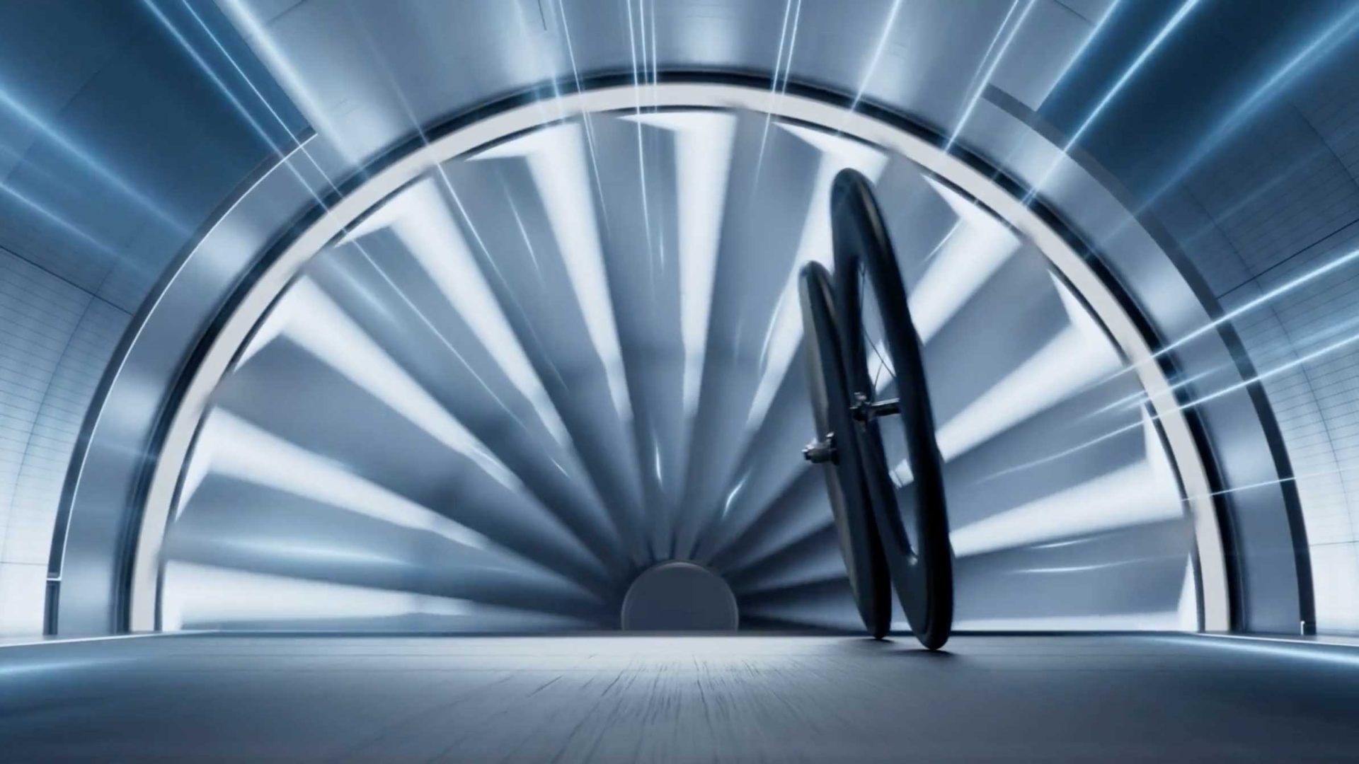 Two bicycle wheels stand upright in a futuristic, silver wind tunnel with radial light beams and a circular, turbine-like design in the background—a striking setting that captures the cutting-edge spirit of Shimano DURA-ACE, as seen in the latest Frame48 campaign film. Frame from Stash Magazine article.