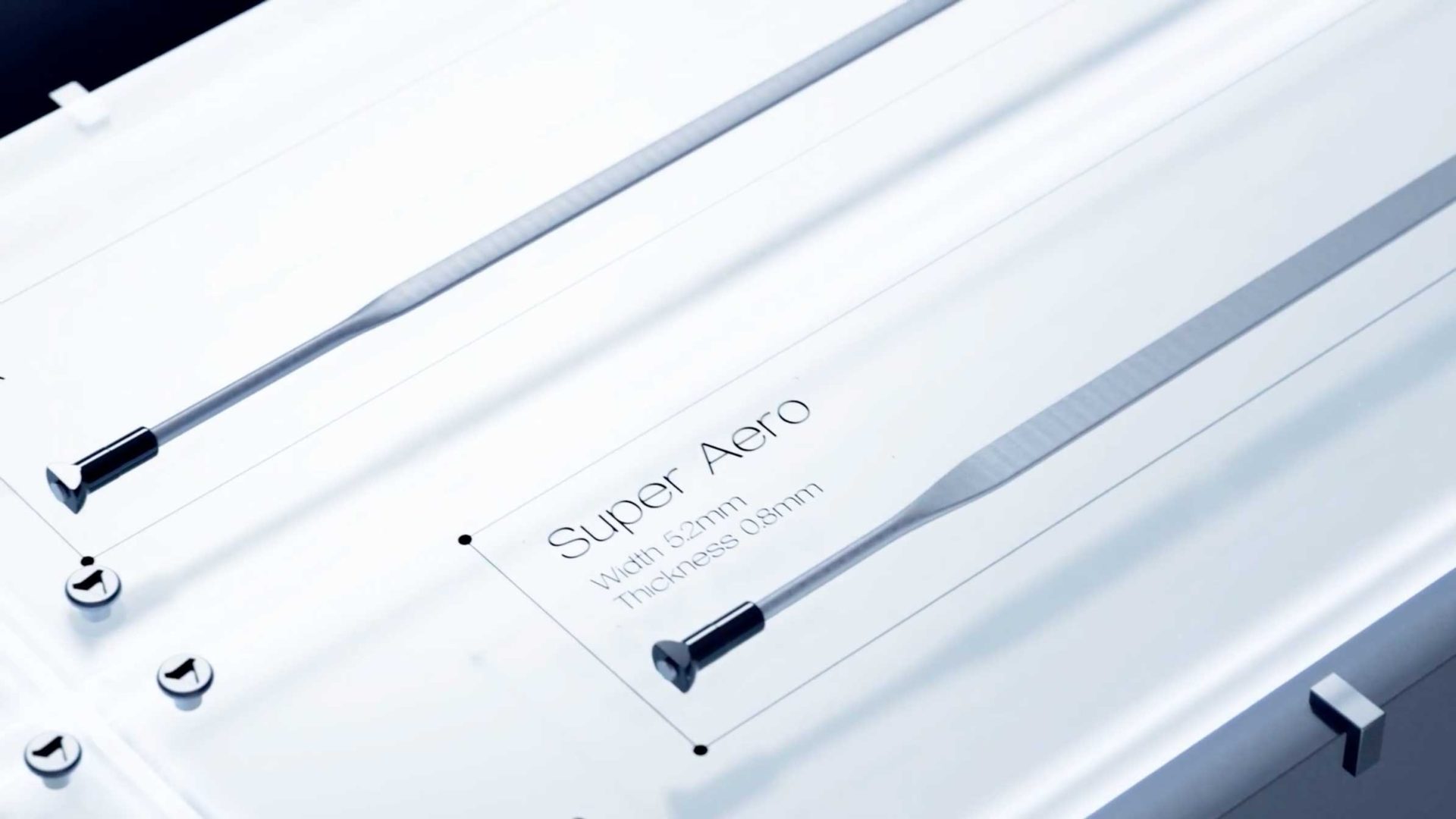 Close-up of a metallic object labeled Super Aero with dimensions: width 52mm and thickness 0.8mm. The image focuses on sleek, silver components with a modern, industrial design, reminiscent of high-performance gear like Shimano DURA-ACE. Frame from Stash Magazine article.