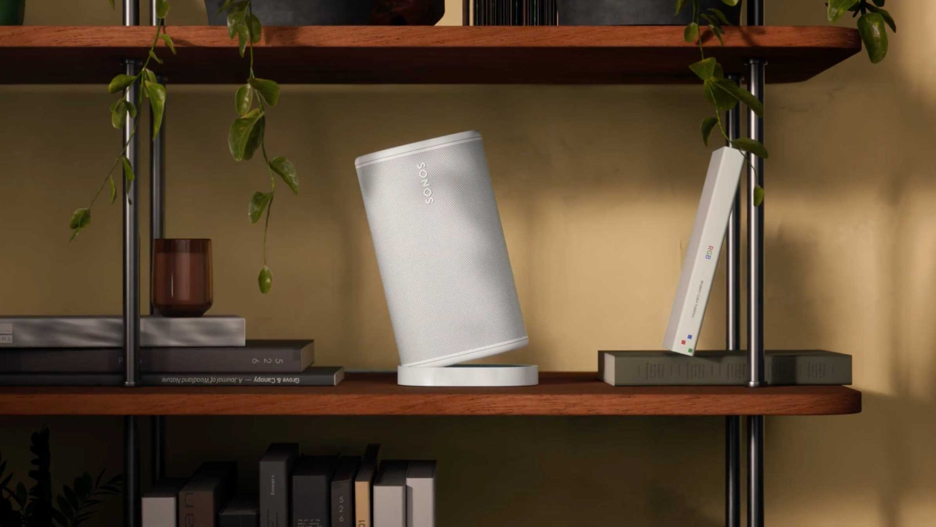 A white Sonos speaker sits on a wooden shelf between a brown glass and a tilted book. Green plants hang down from the shelf above, while several books and playful decor line up below—setting the perfect scene for your next brand film. Frame from Stash Magazine article.