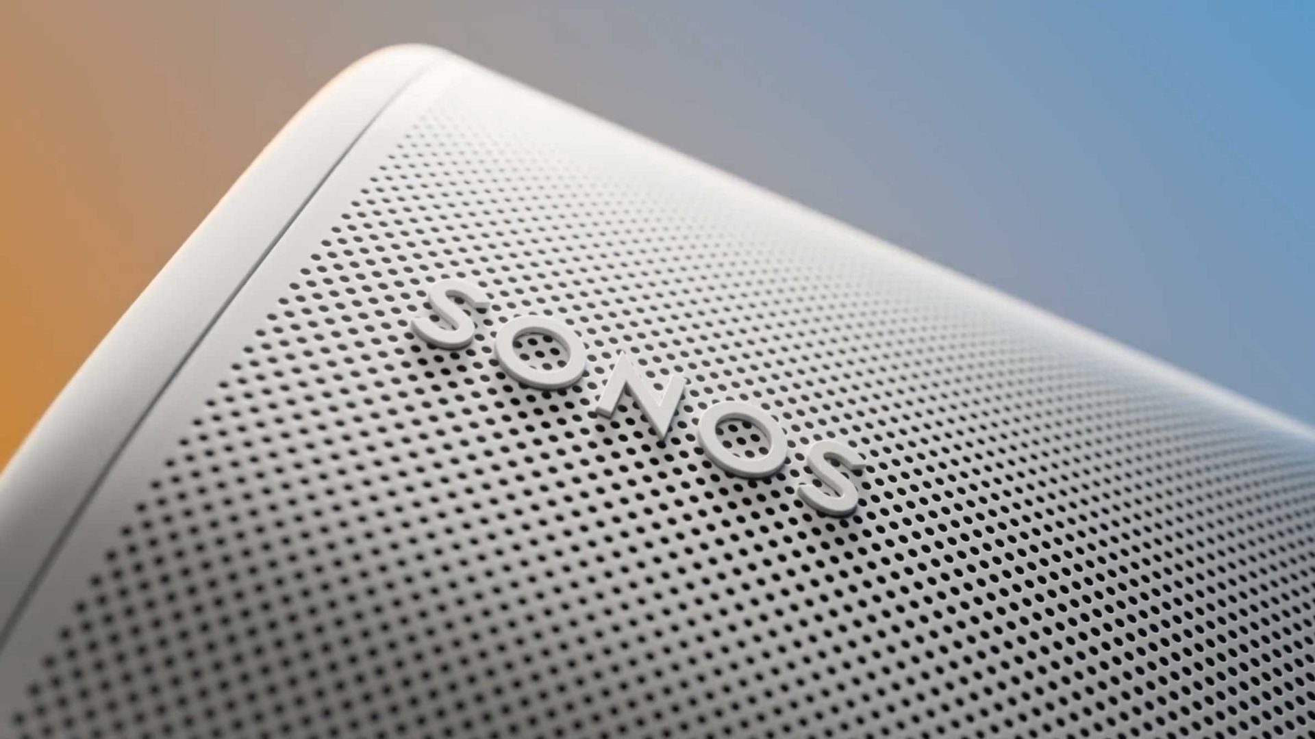 Close-up of a white Sonos speaker, showing the perforated grille and raised SONOS logo. The background fades from orange to blue, giving a modern and sleek appearance—perfect for any brand film or for when you hit Play on your favorite tracks. Frame from Stash Magazine article.