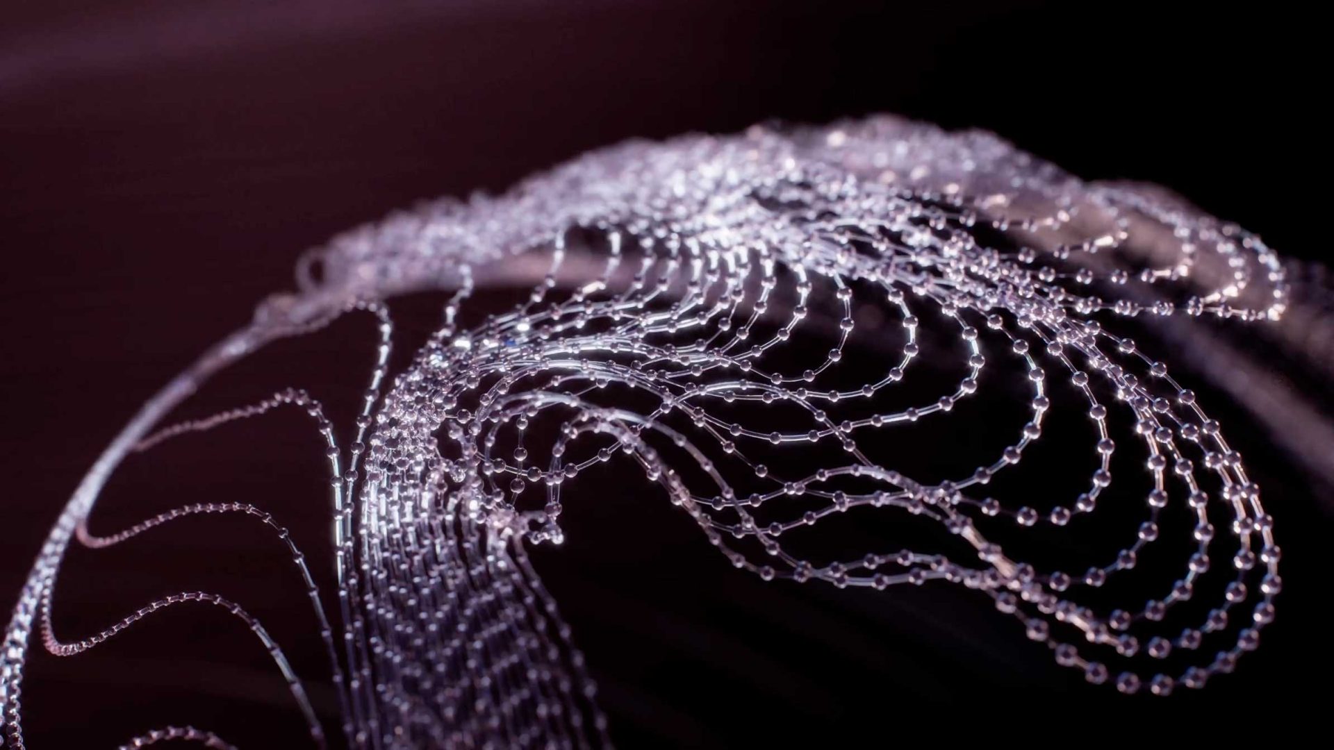 Close-up of delicate, swirling strands of tiny water droplets suspended in midair against a dark, out-of-focus background, creating an abstract, wave-like pattern reminiscent of the mesmerizing visuals found in the Spheres demo reel by Vladislav Solovjov. Frame from Stash Magazine article.