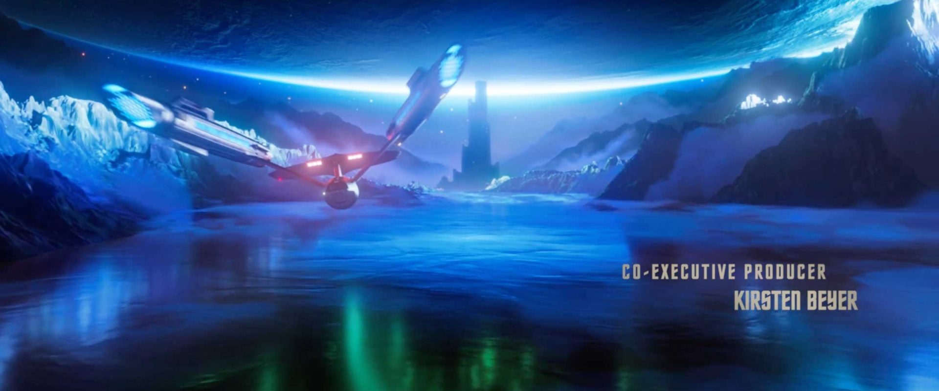 A futuristic Star Trek spaceship flies over an icy blue landscape with mountains and a tower, beneath a glowing planet. Text reads: Co-Executive Producer Kirsten Beyer. This scene captures the wonder of Strange New Worlds in Season 4. Frame from Stash Magazine article.