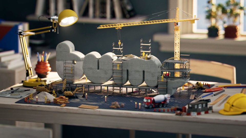 A desk with a miniature construction scene—workers, scaffolding, and cranes from Studio Bump Underconstruction building concrete letters spelling "home." Tools, blueprints, and construction vehicles are scattered around. Frame from Stash Magazine article.