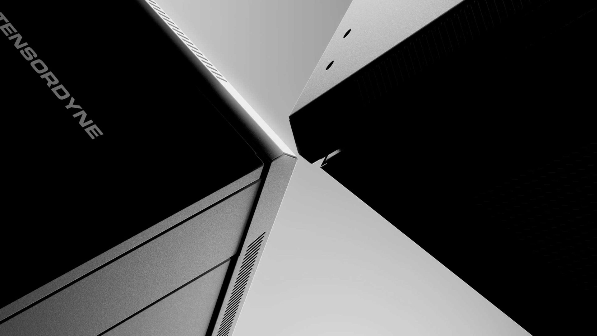 Close-up, black-and-white image of three modern, angular electronic devices or computer towers—possibly Tensordyne models—arranged with their corners nearly touching, creating geometric patterns. “SENSOR DYN E” is partially visible on one device. Frame from Stash Magazine article.