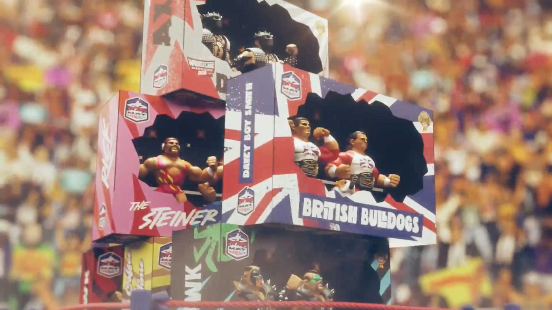 Three display boxes featuring wrestling action figures are stacked in a crowded arena, reminiscent of The Golden Era of Wrestling promo video by Cub Studio. The boxes—The Steiner, British Bulldogs, and Demolition—hold detailed wrestler figurines. Frame from Stash Magazine article.